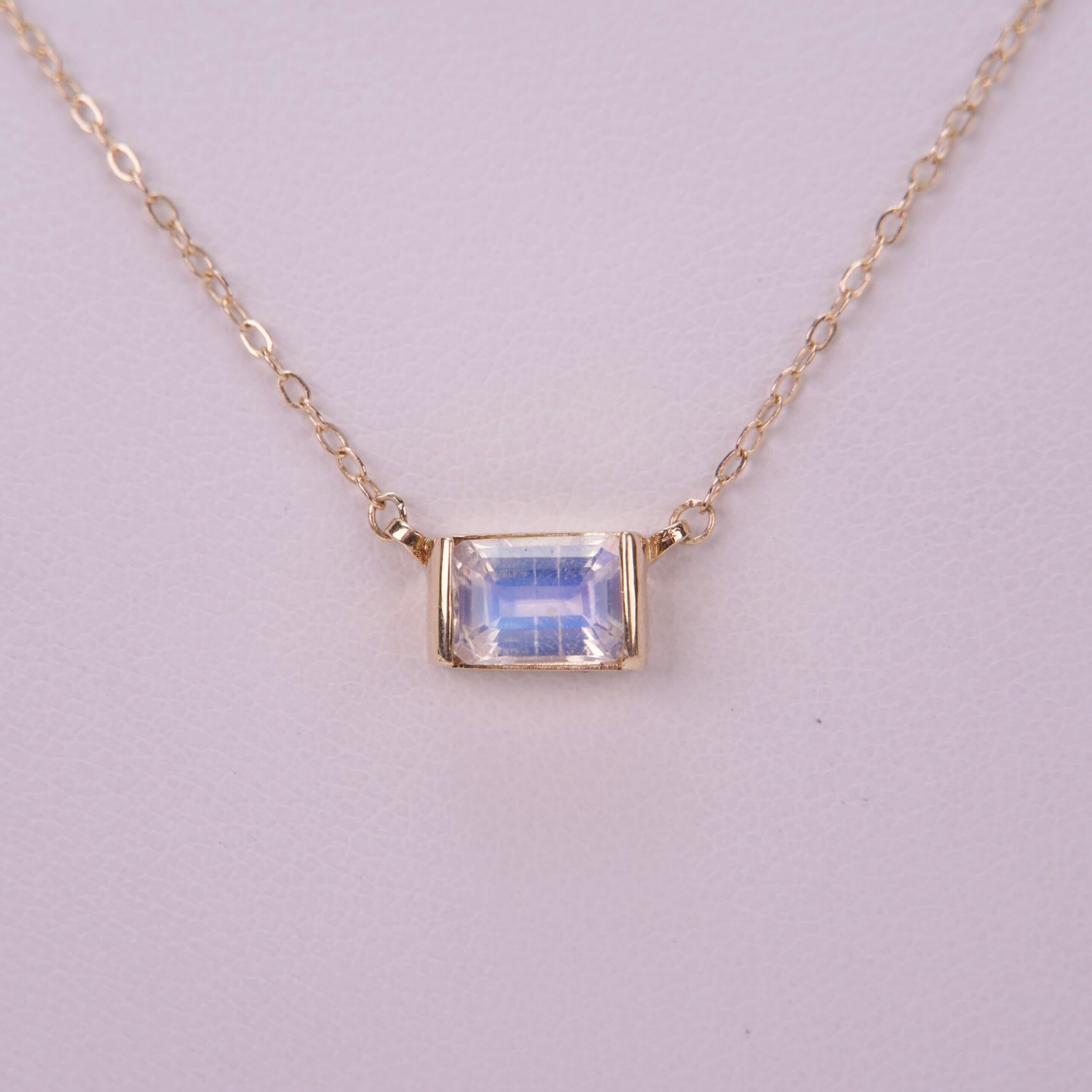 Gold chain necklace with rectangular gemstone.