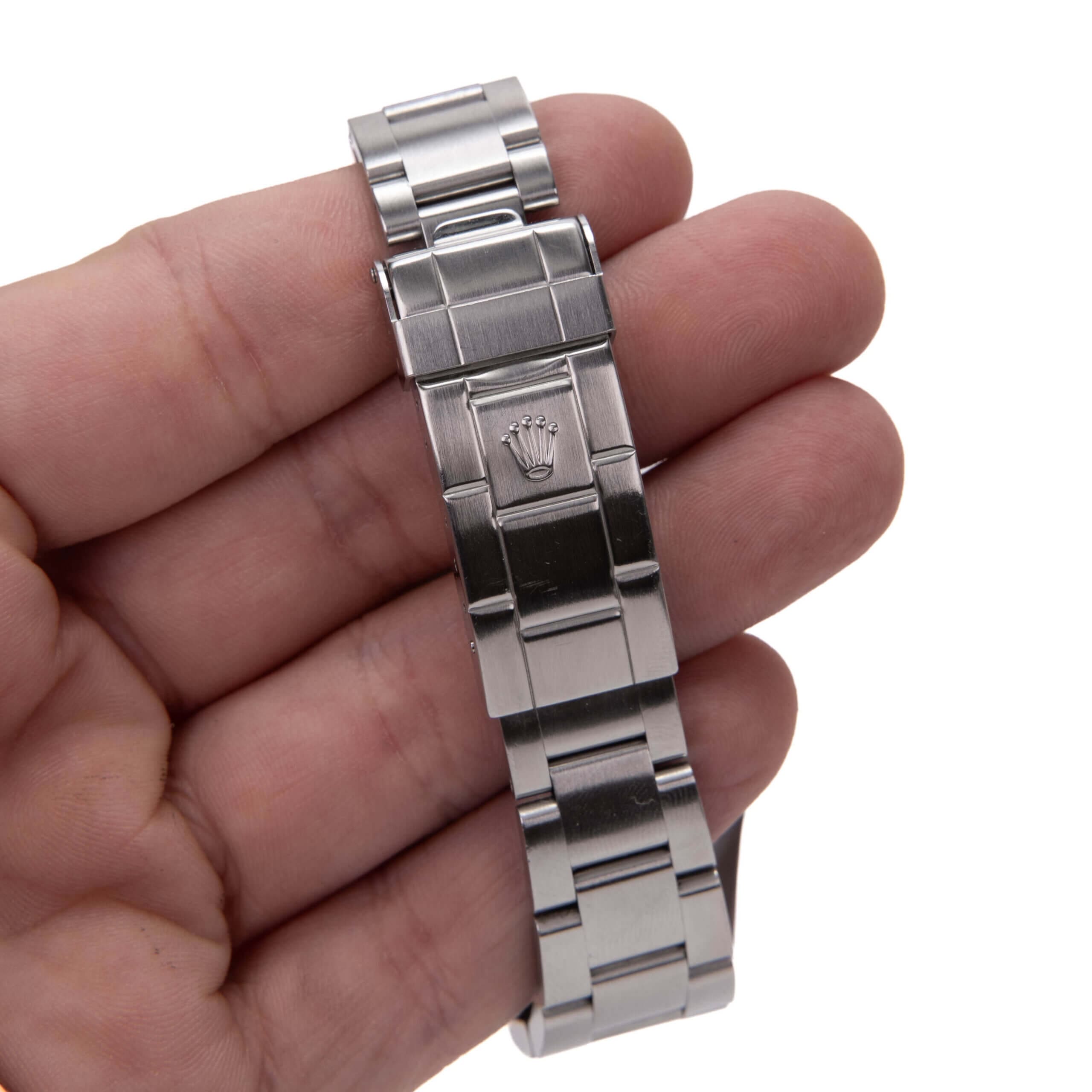Hand holding a stainless steel watch bracelet.