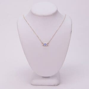 Gold necklace with a square gemstone pendant.