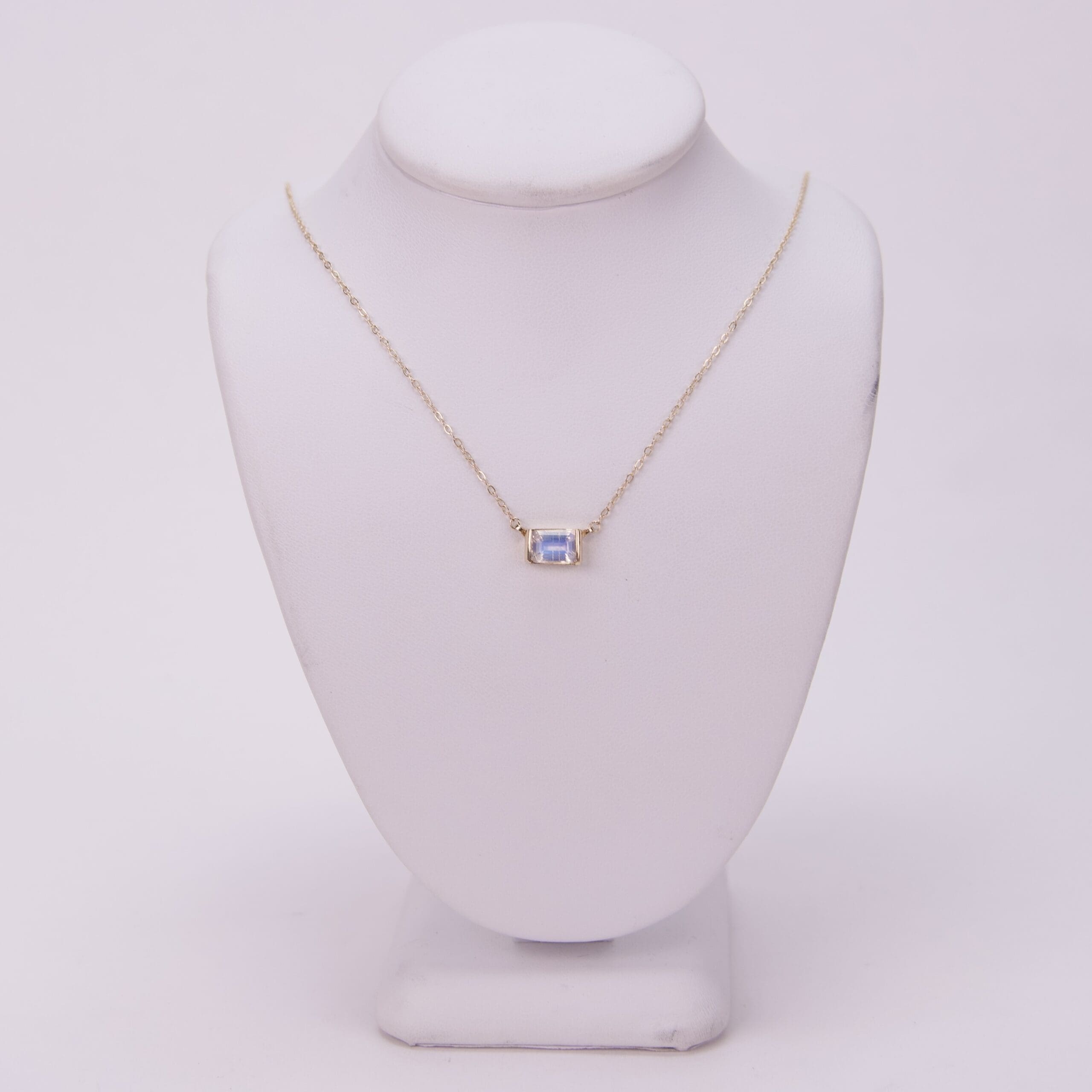 Gold necklace with a square gemstone pendant.