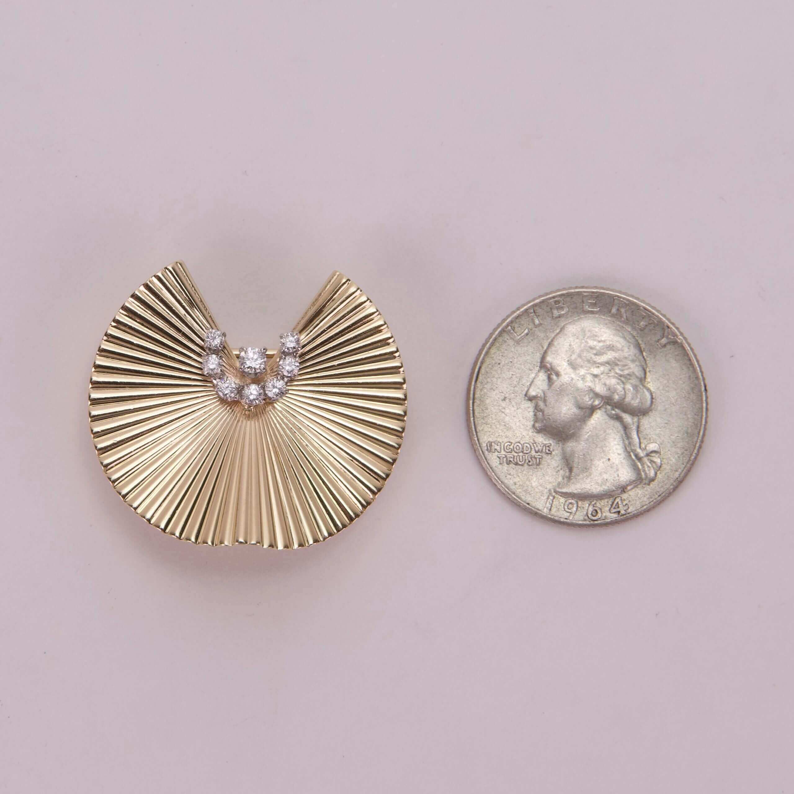 Gold brooch with diamonds, beside US quarter.