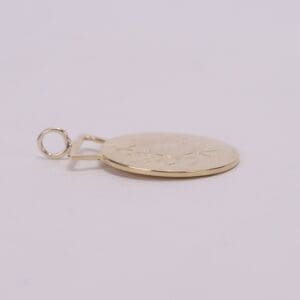 Gold pendant with engraved leaf design.