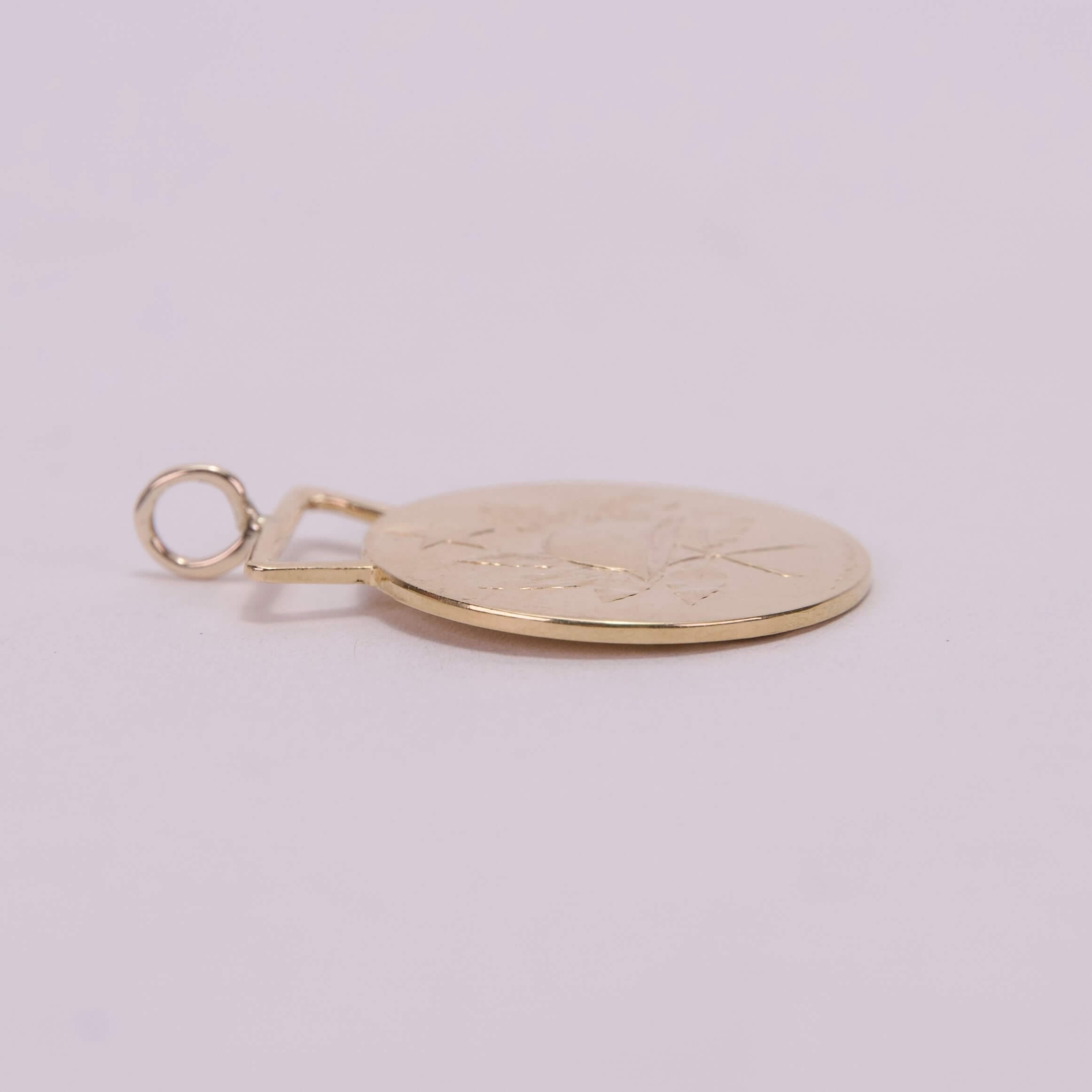 Gold pendant with engraved leaf design.