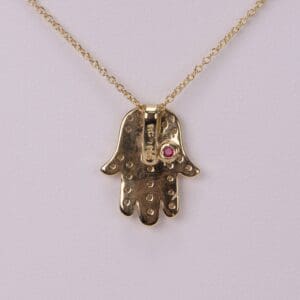 Gold Hamsa necklace with pink gem.