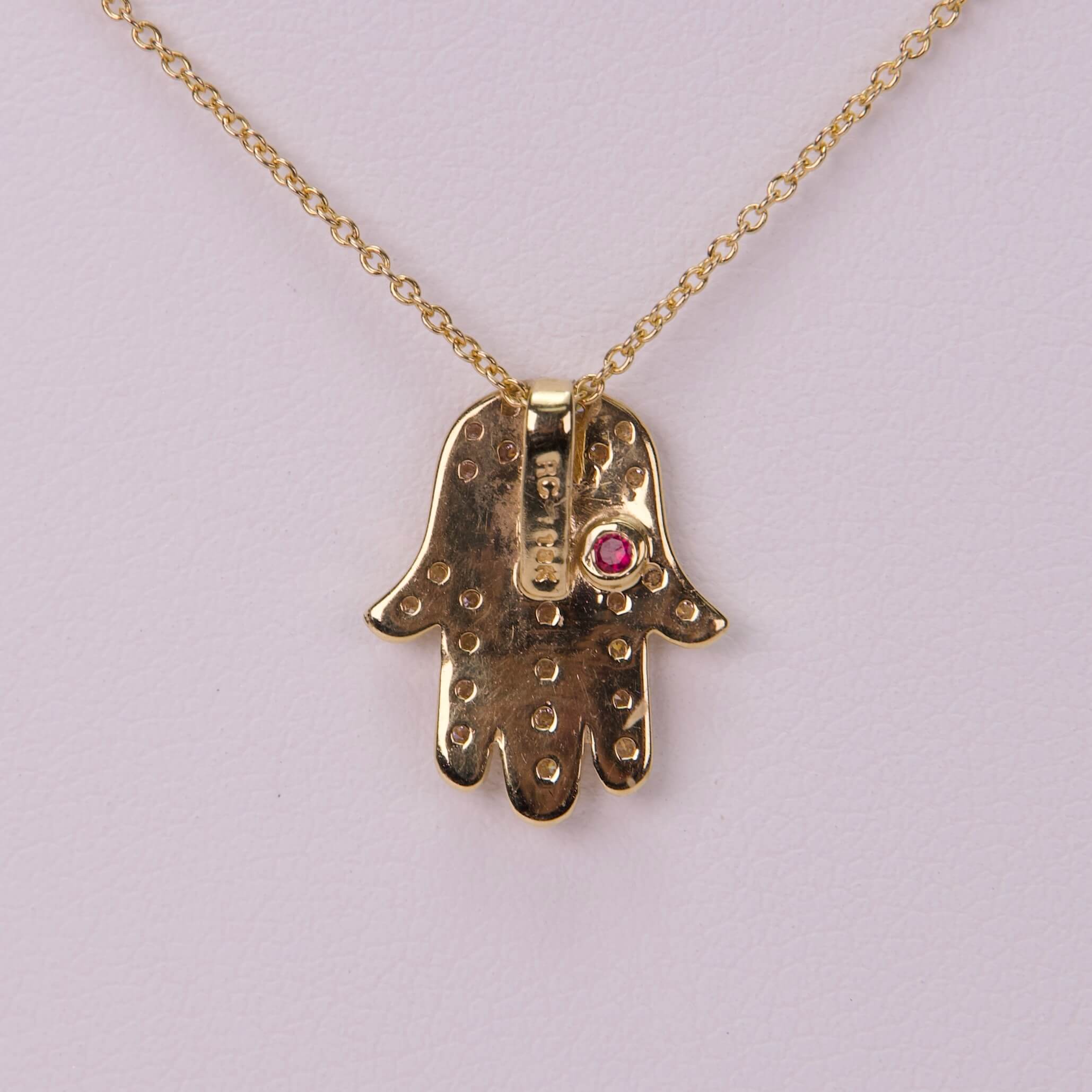 Gold Hamsa necklace with pink gem.