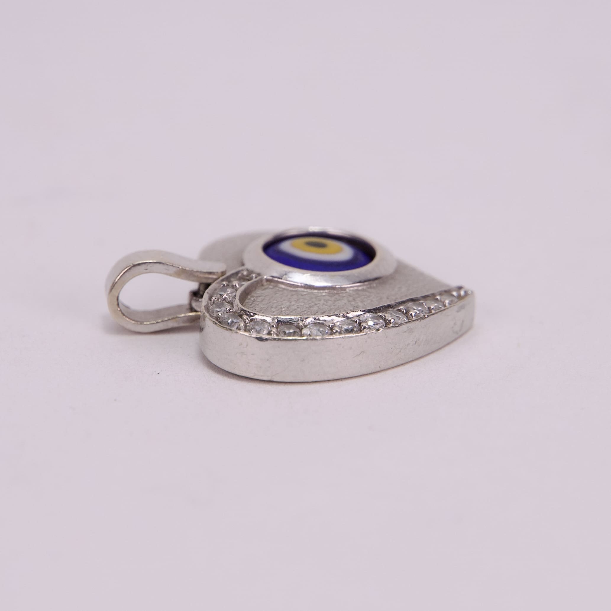 Silver eye-shaped pendant with rhinestones.