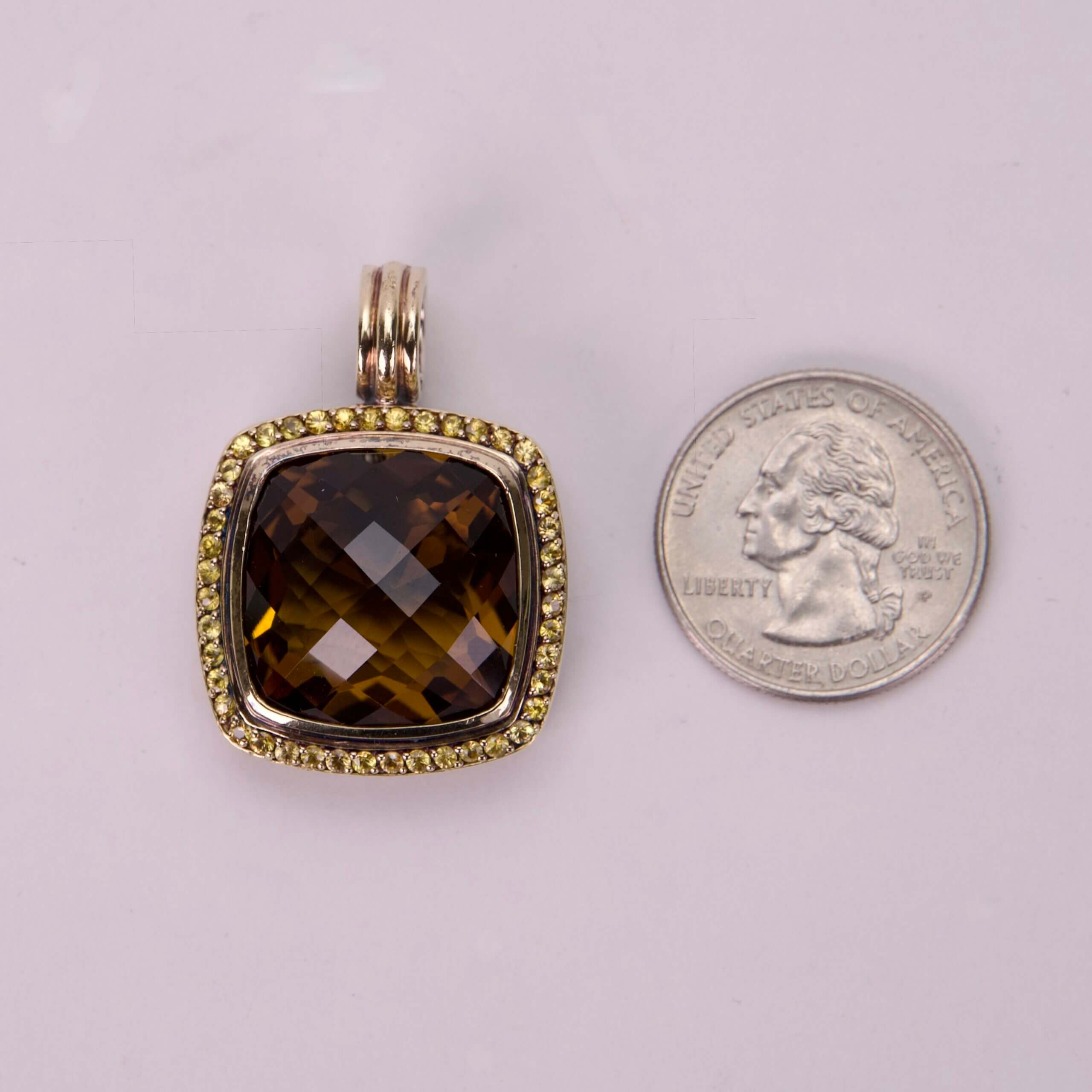 Brown gemstone pendant beside a quarter coin.