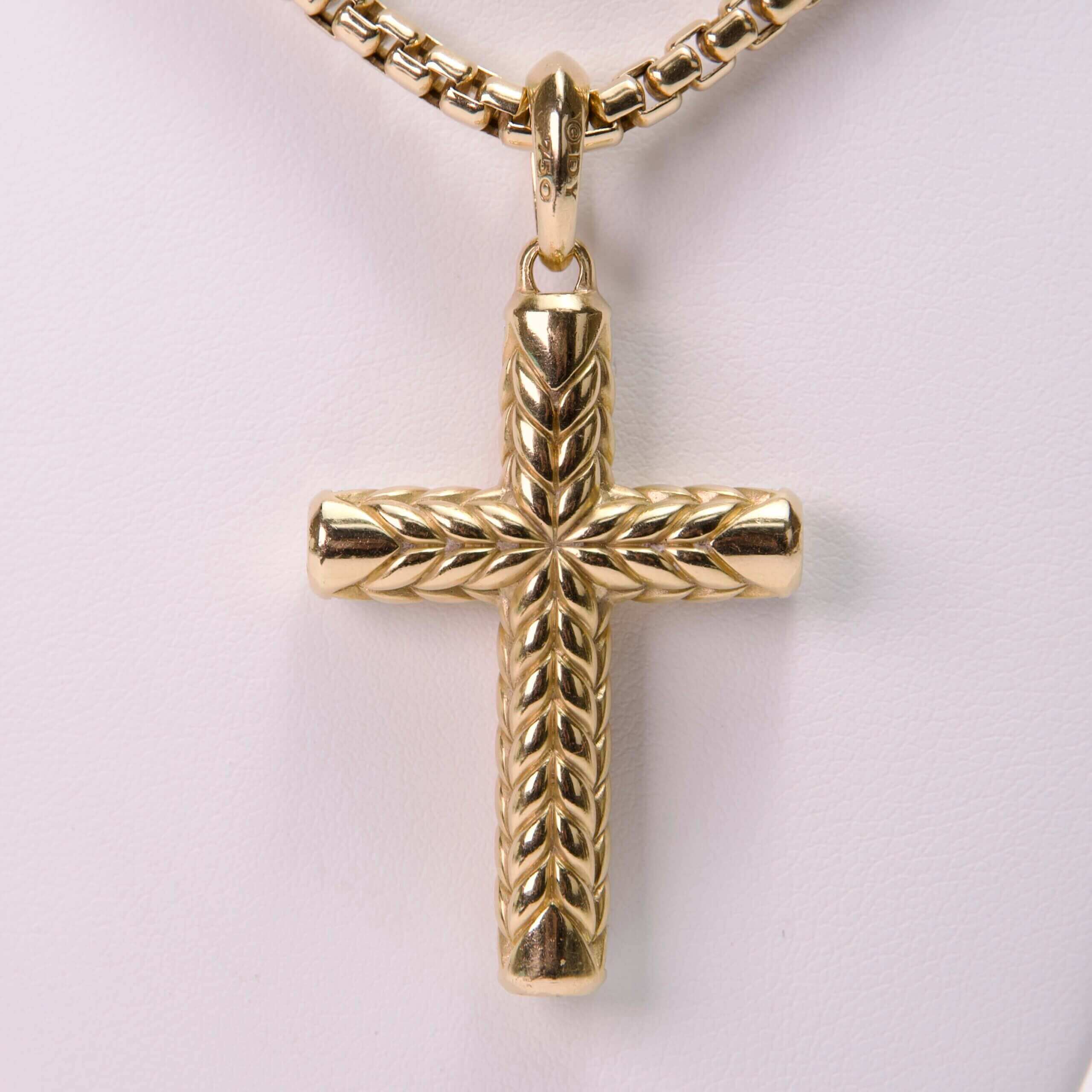 Gold cross pendant with intricate design.