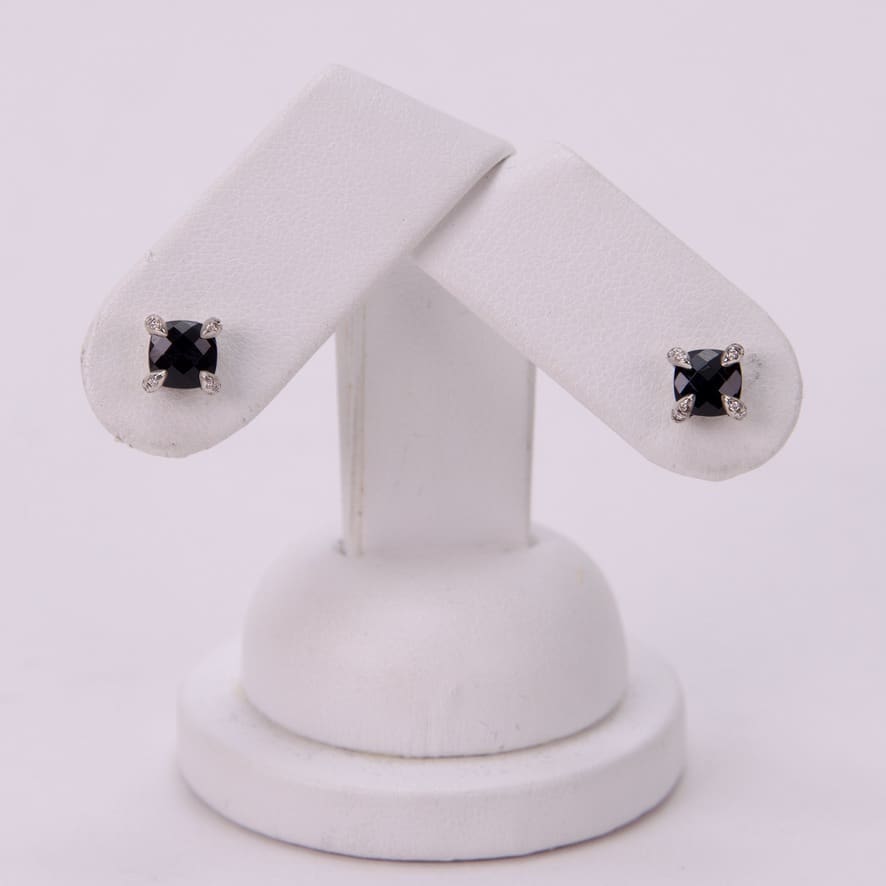 Black stud earrings on white display stand.