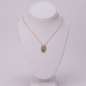 Gold necklace with Hamsa pendant on display.