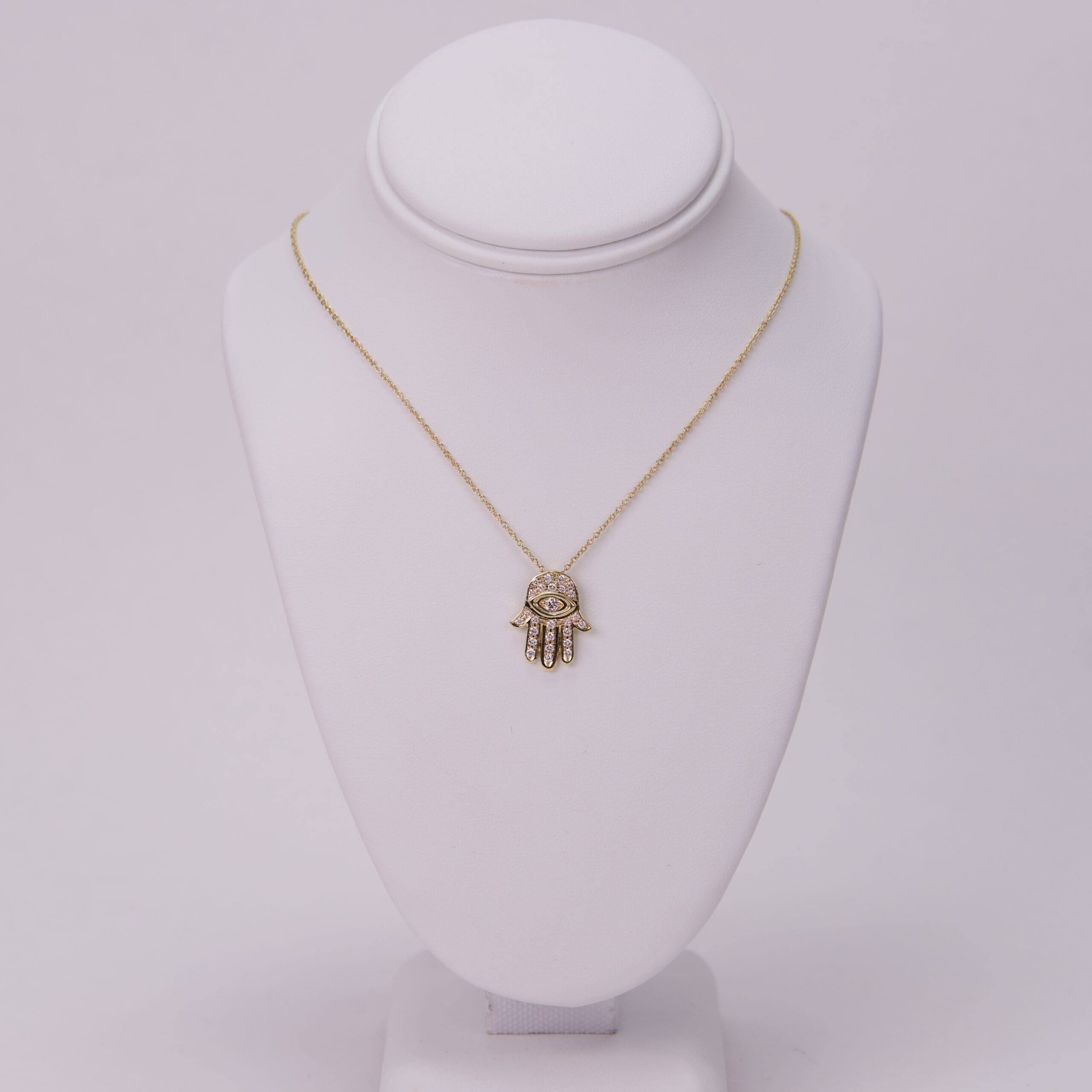 Gold necklace with Hamsa pendant on display.