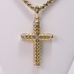 Gold cross pendant with intricate braided design.