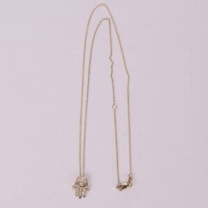 Gold necklace with Hamsa hand pendant.
