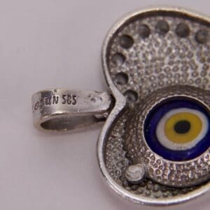 Silver pendant with evil eye design.