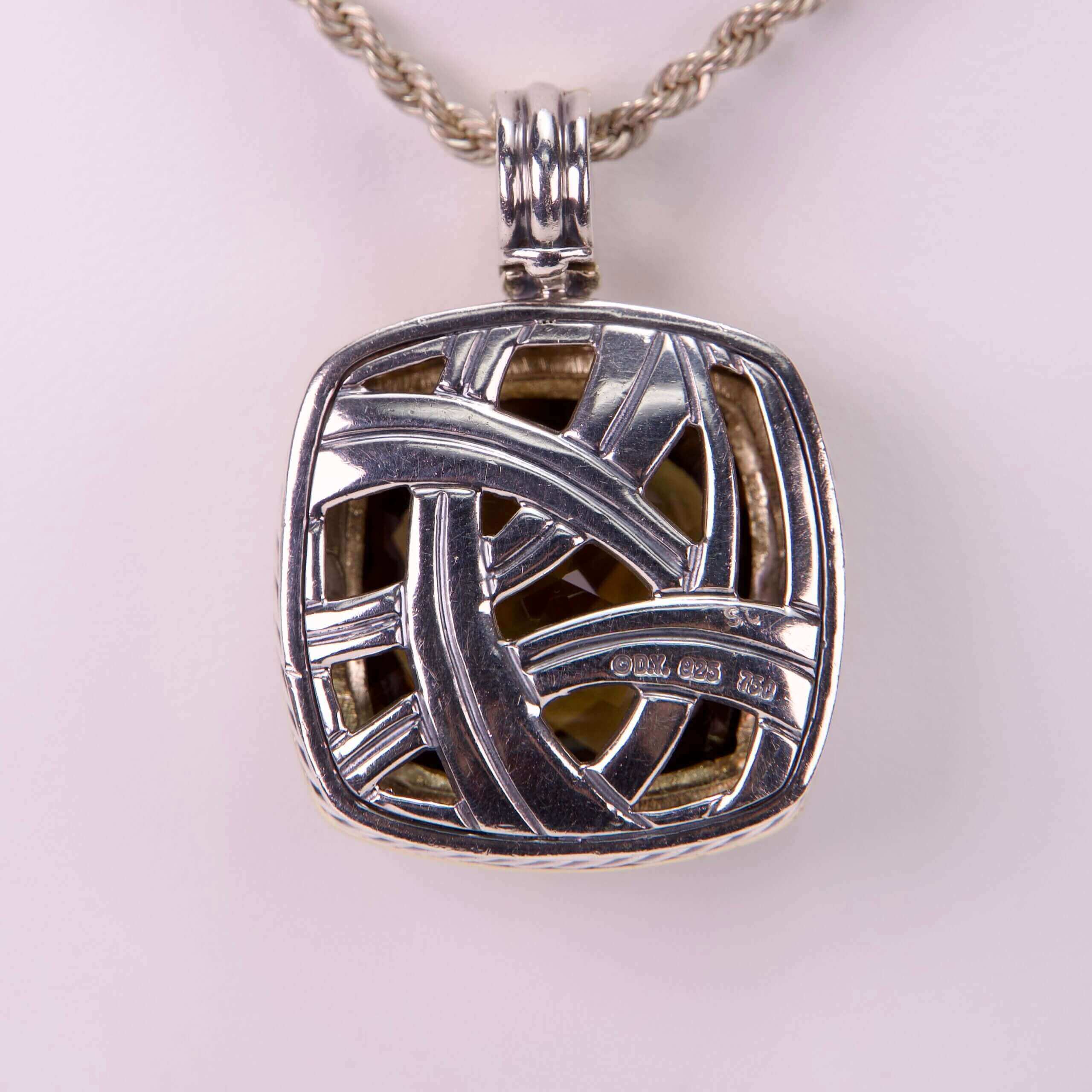 Silver pendant with intricate woven design.