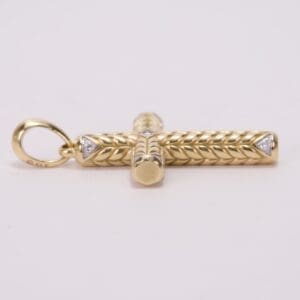 Gold cross pendant with intricate design.