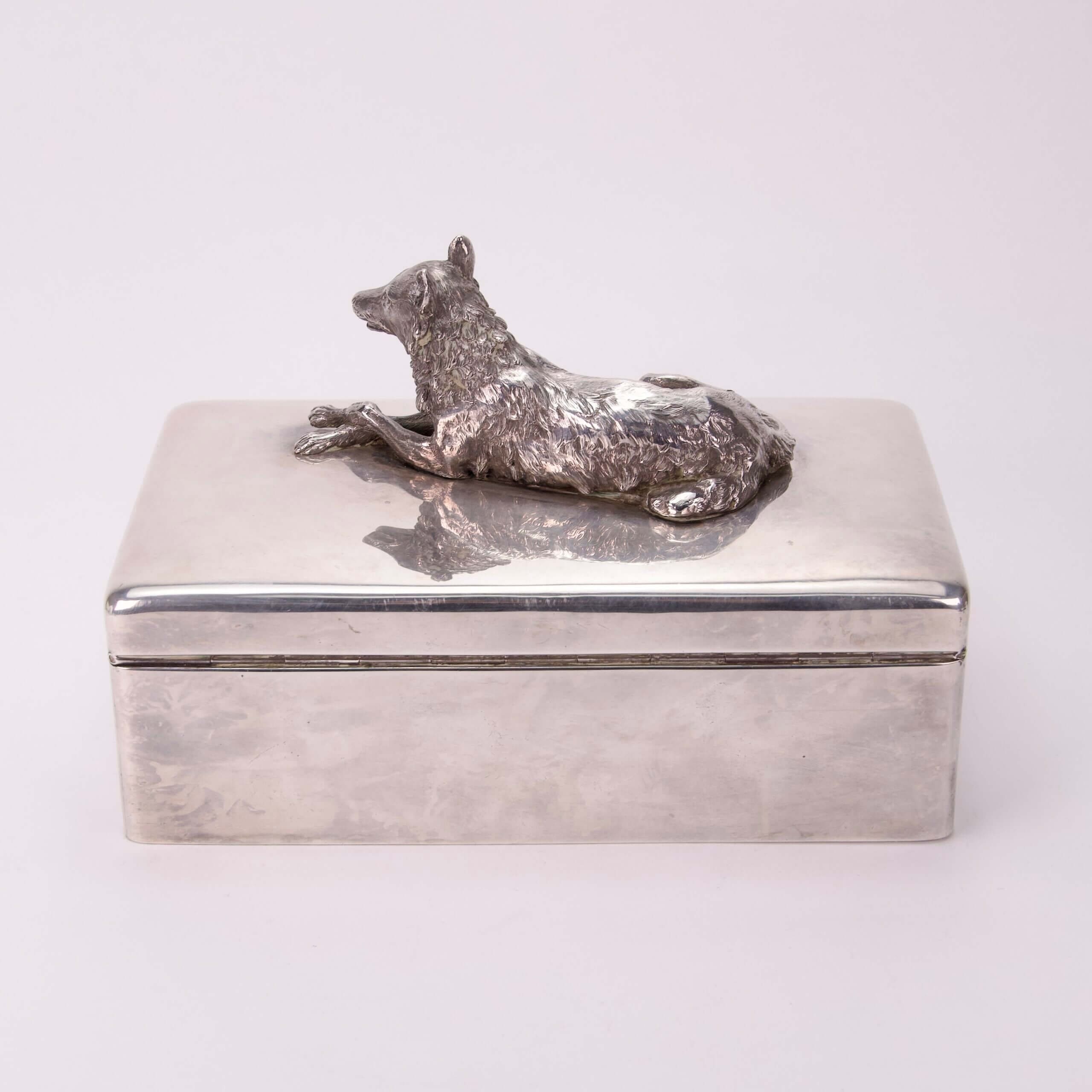 Silver box with wolf figurine on lid.
