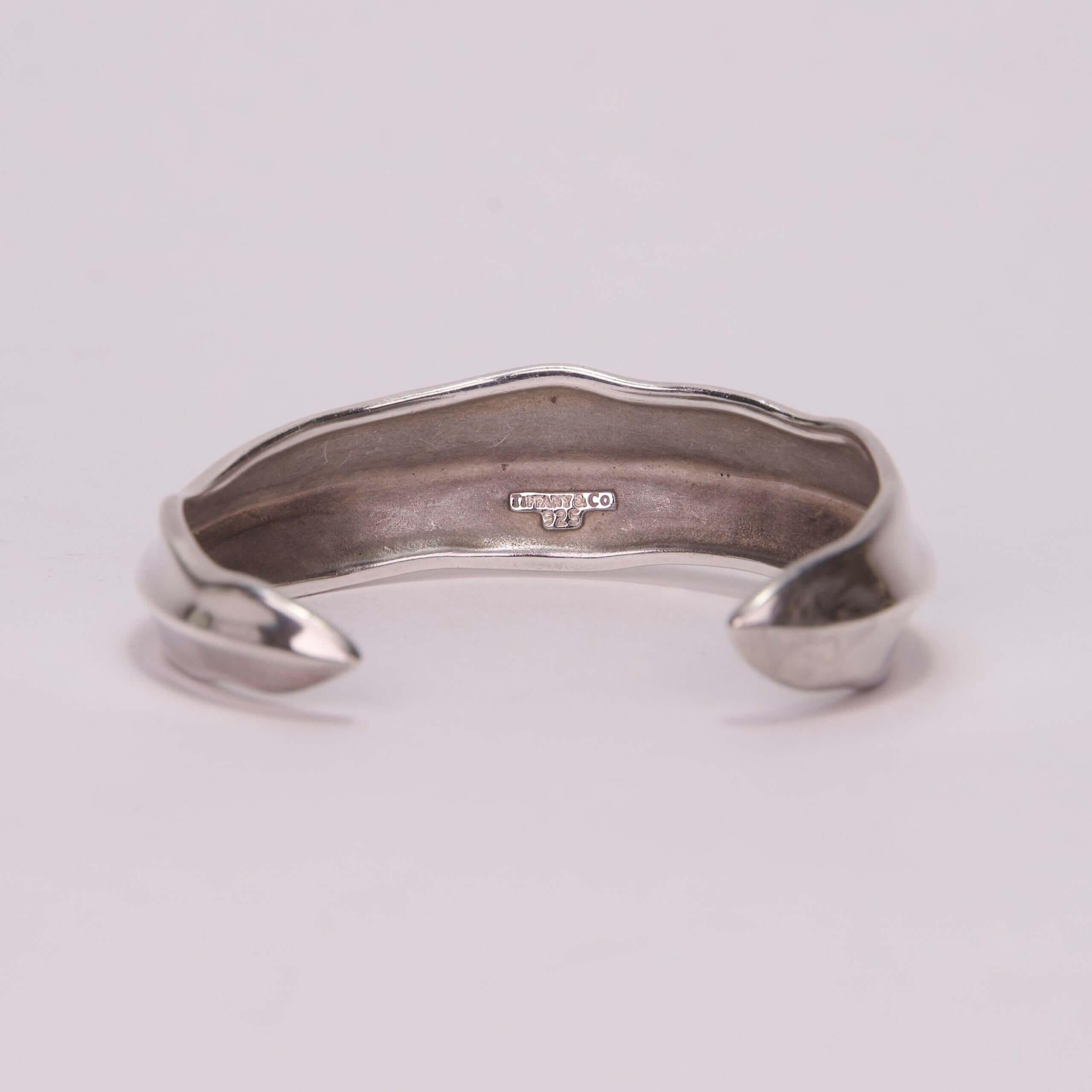 Silver cuff bracelet with engraved details.