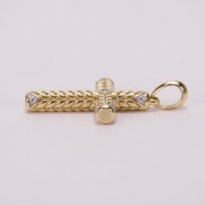 Gold cross pendant with intricate braid design.