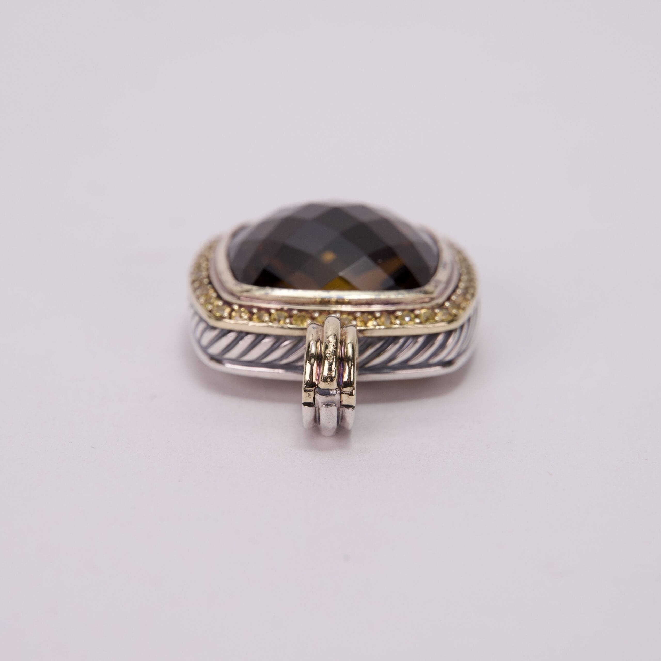 Silver and gold pendant with dark gemstone.