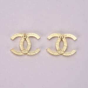 Gold Chanel logo earrings on display.
