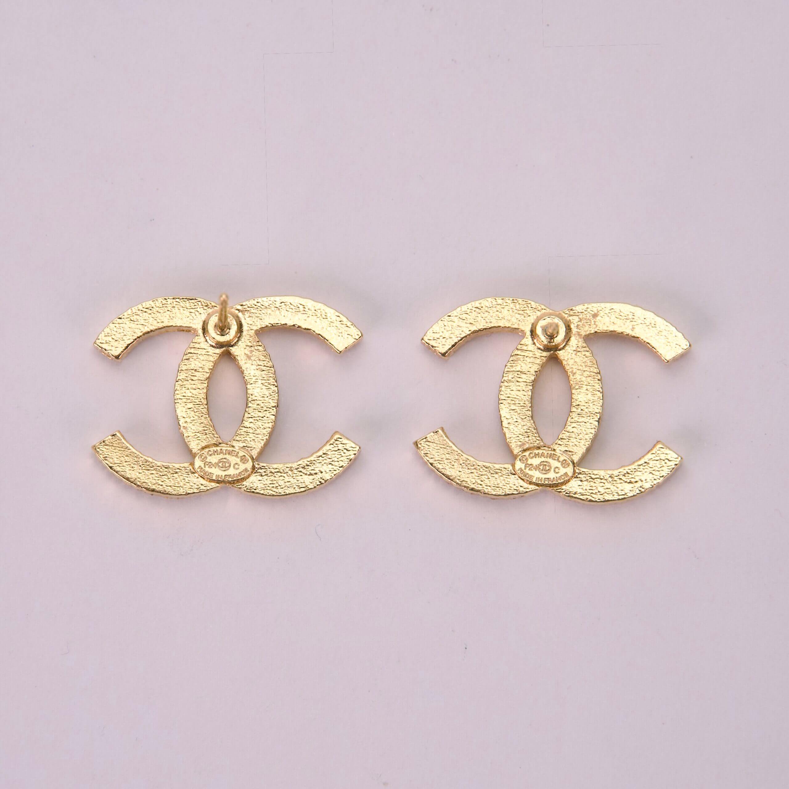 Gold Chanel logo earrings on display.