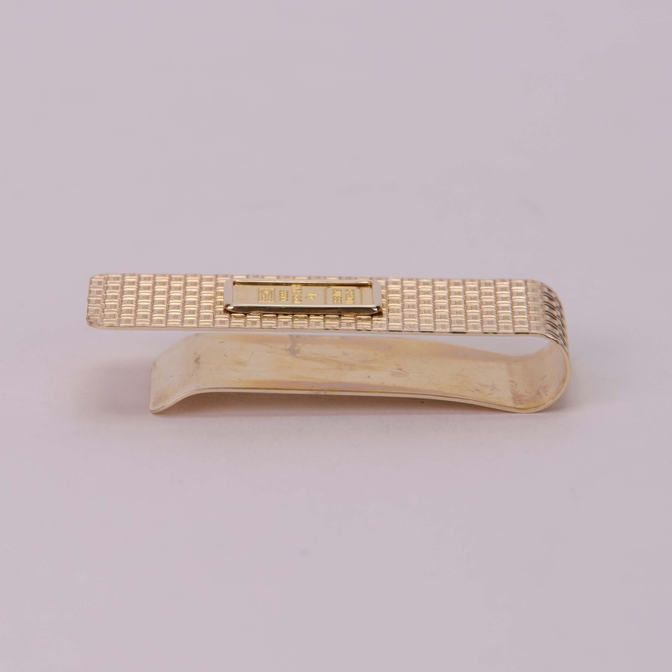 Gold textured money clip on white background.