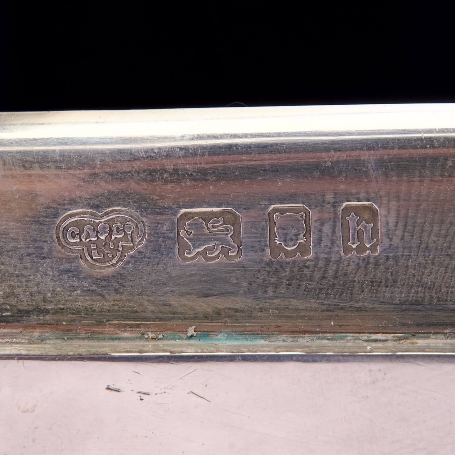 Silver hallmark with various engraved symbols.