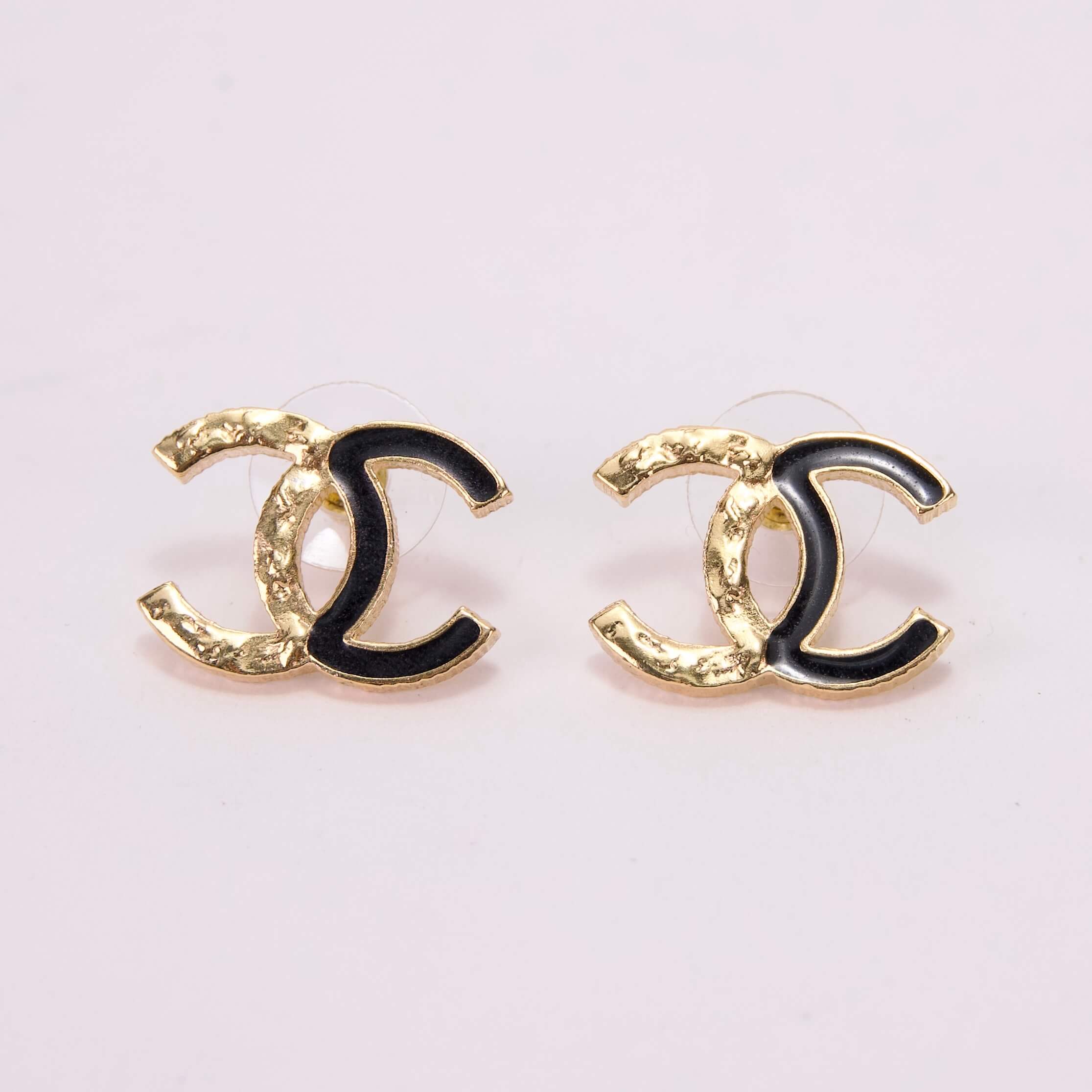 Gold and black logo earrings on display.