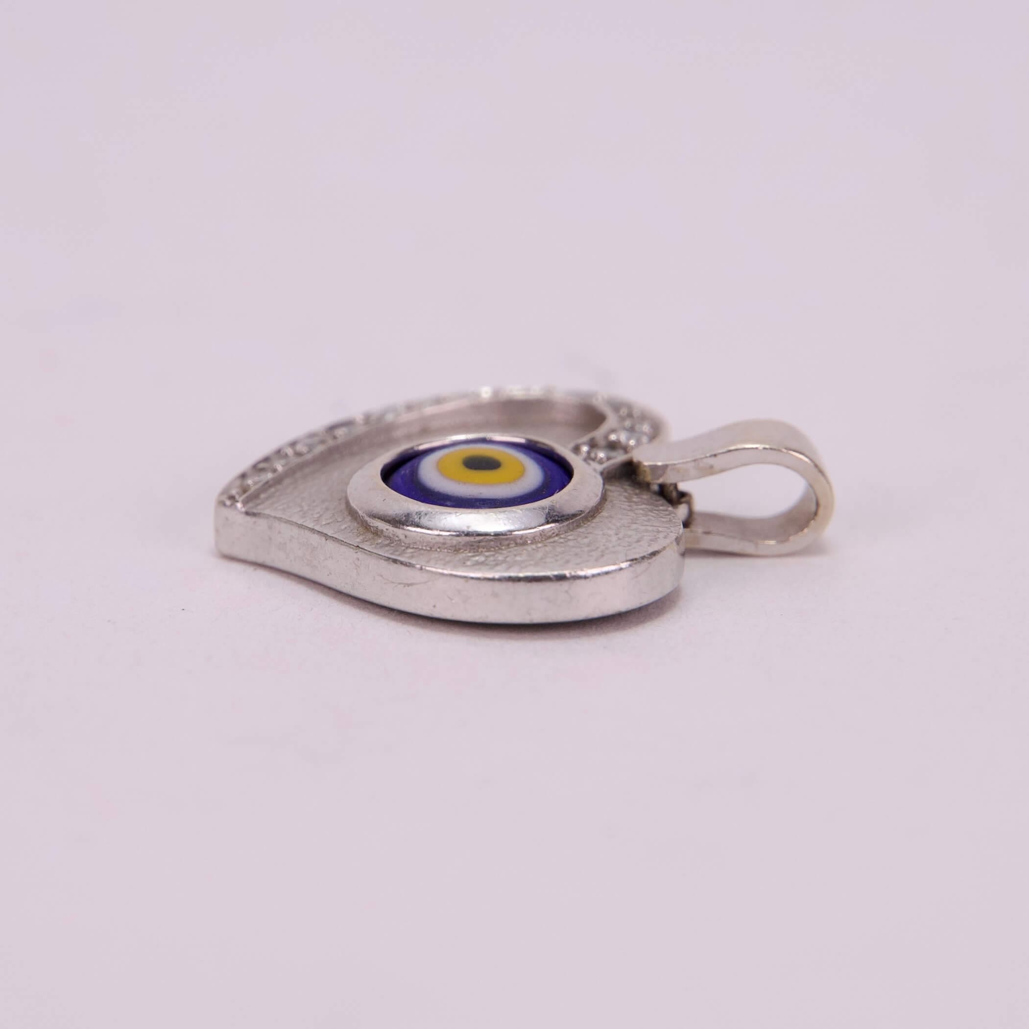 Heart-shaped silver pendant with evil eye.