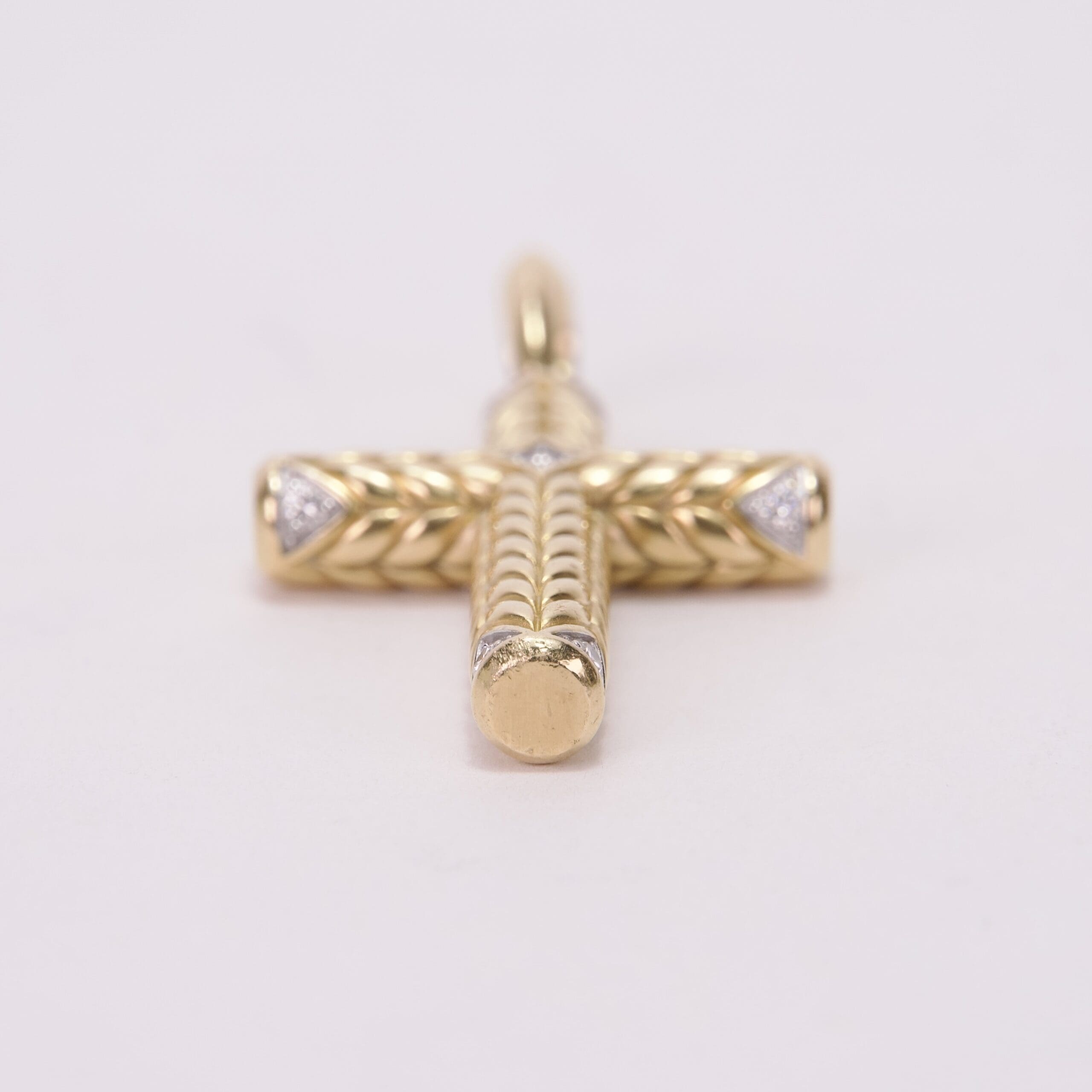 Gold cross pendant with intricate design.