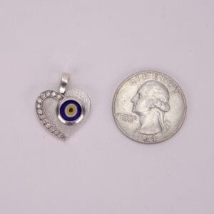 Heart-shaped pendant beside a quarter coin.