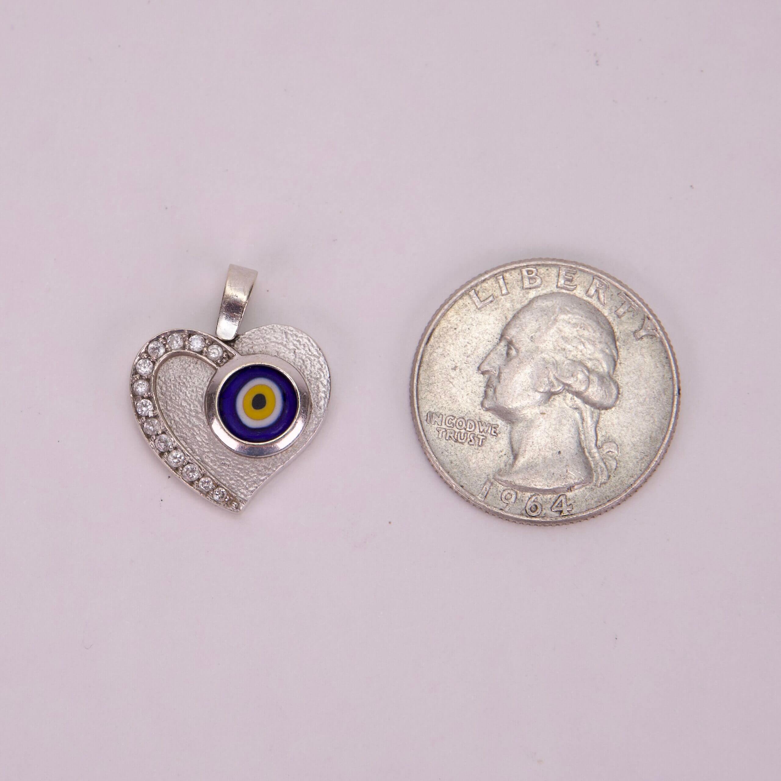 Heart-shaped pendant beside a quarter coin.
