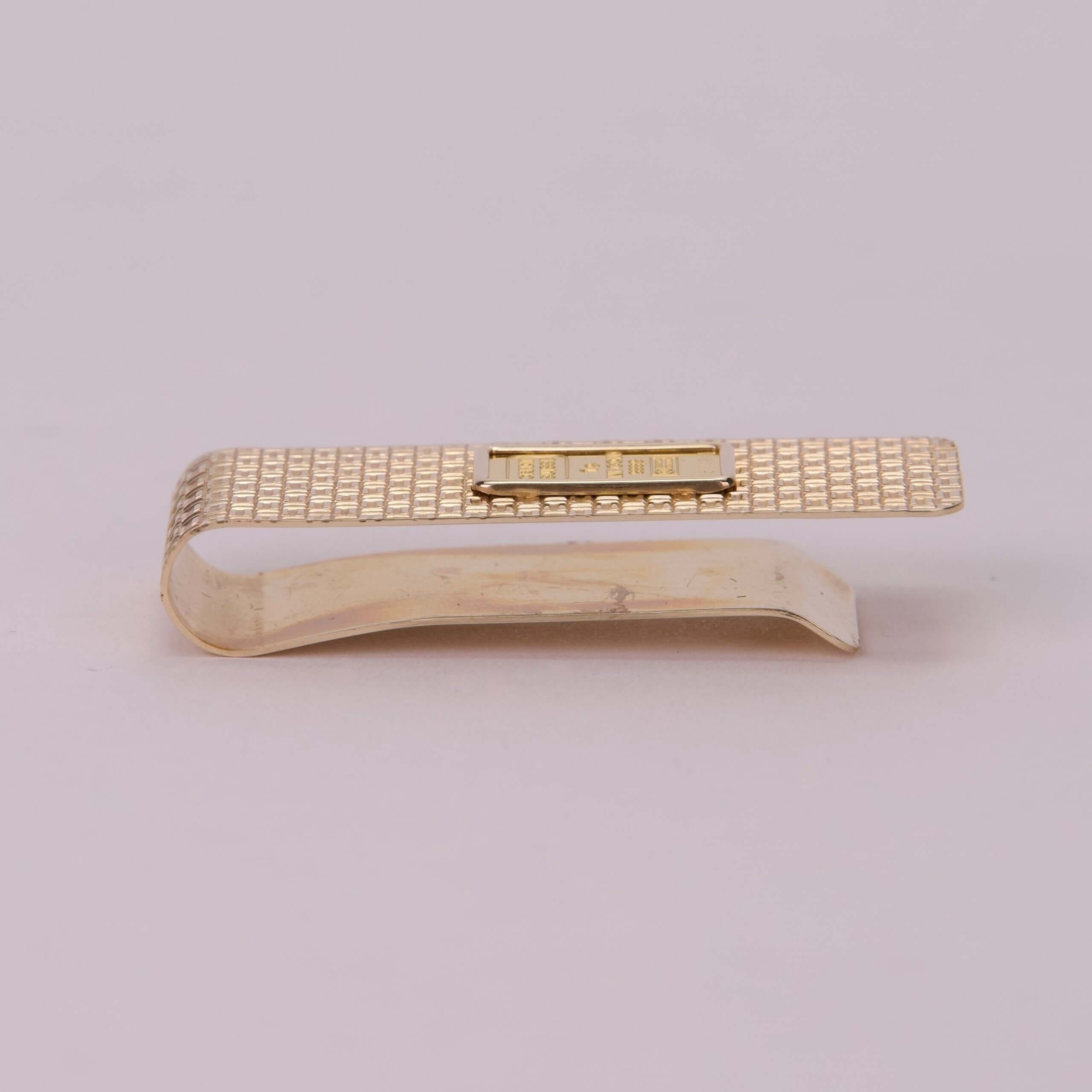 Gold textured money clip on white background.
