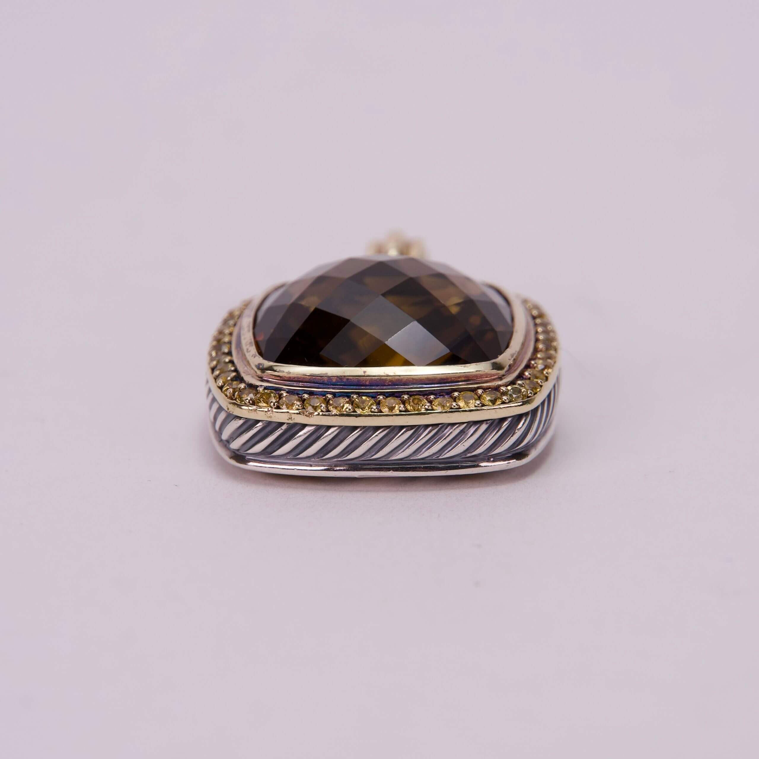 Silver and gold pendant with dark gemstone.