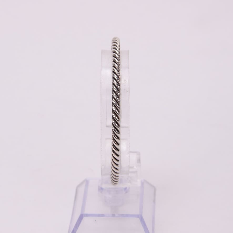 Silver twisted rope design bracelet on stand.