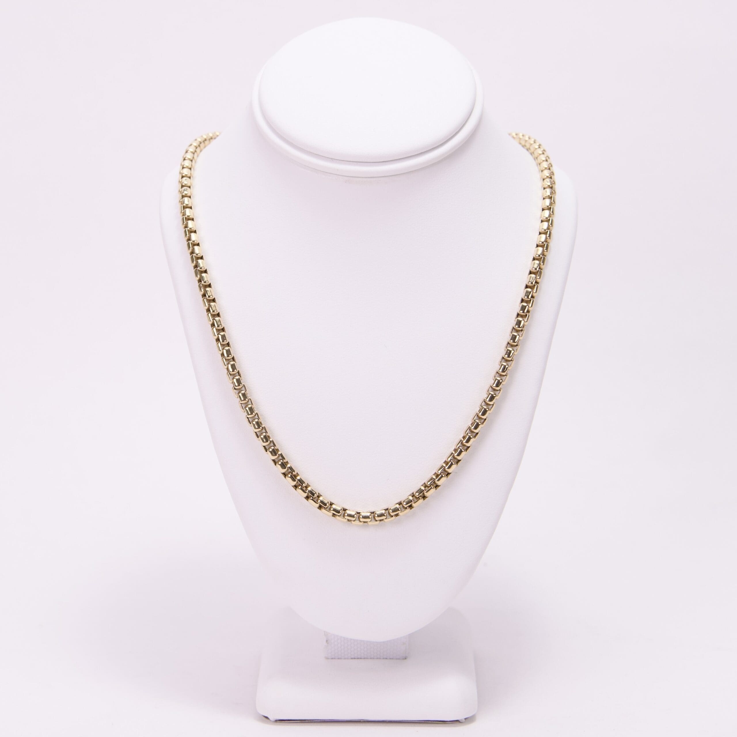 Gold chain necklace on display stand.