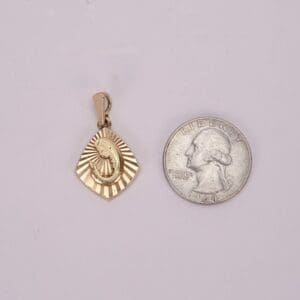 Gold pendant beside a quarter coin.