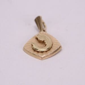 Gold pendant with a fish design.