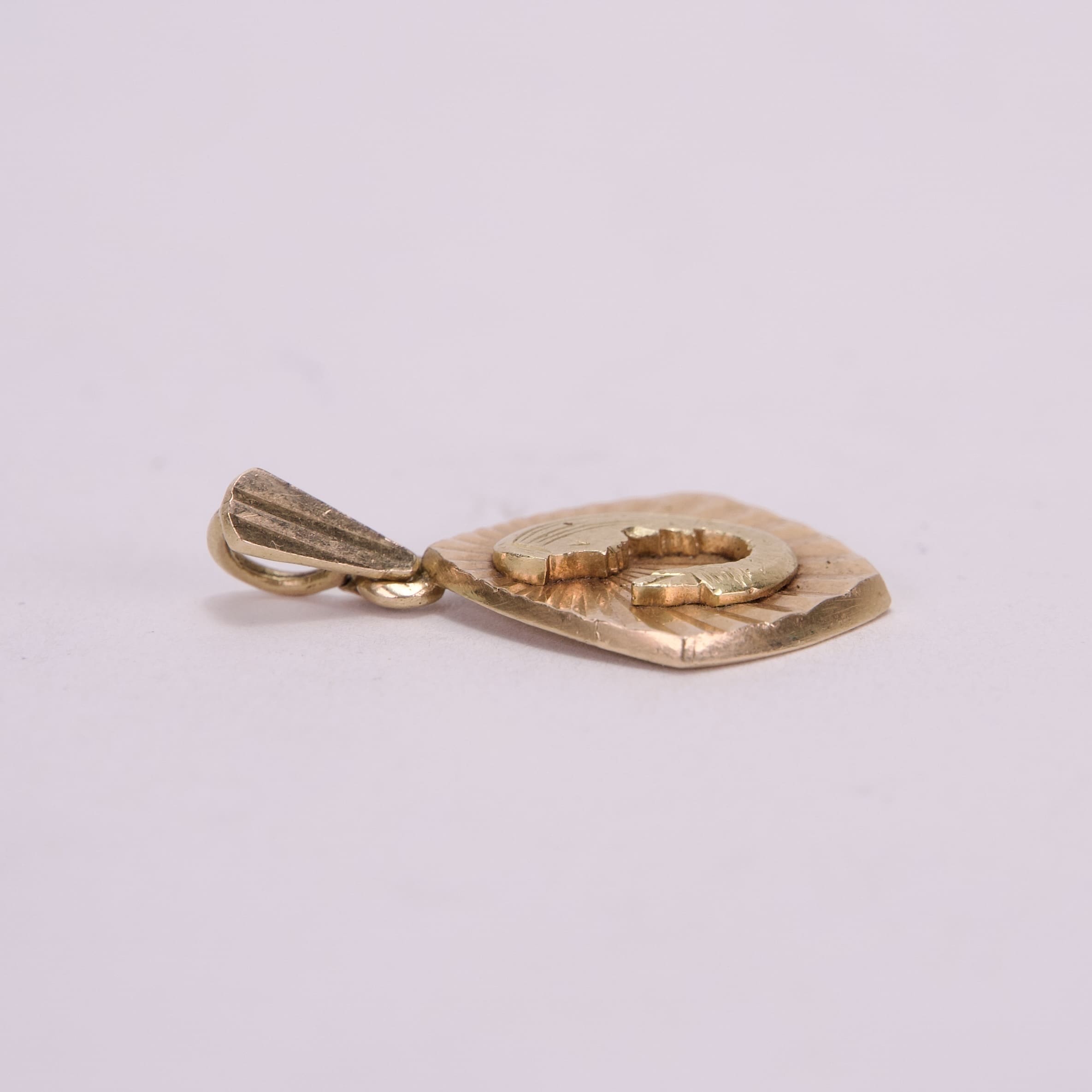 Gold pendant with embossed design.