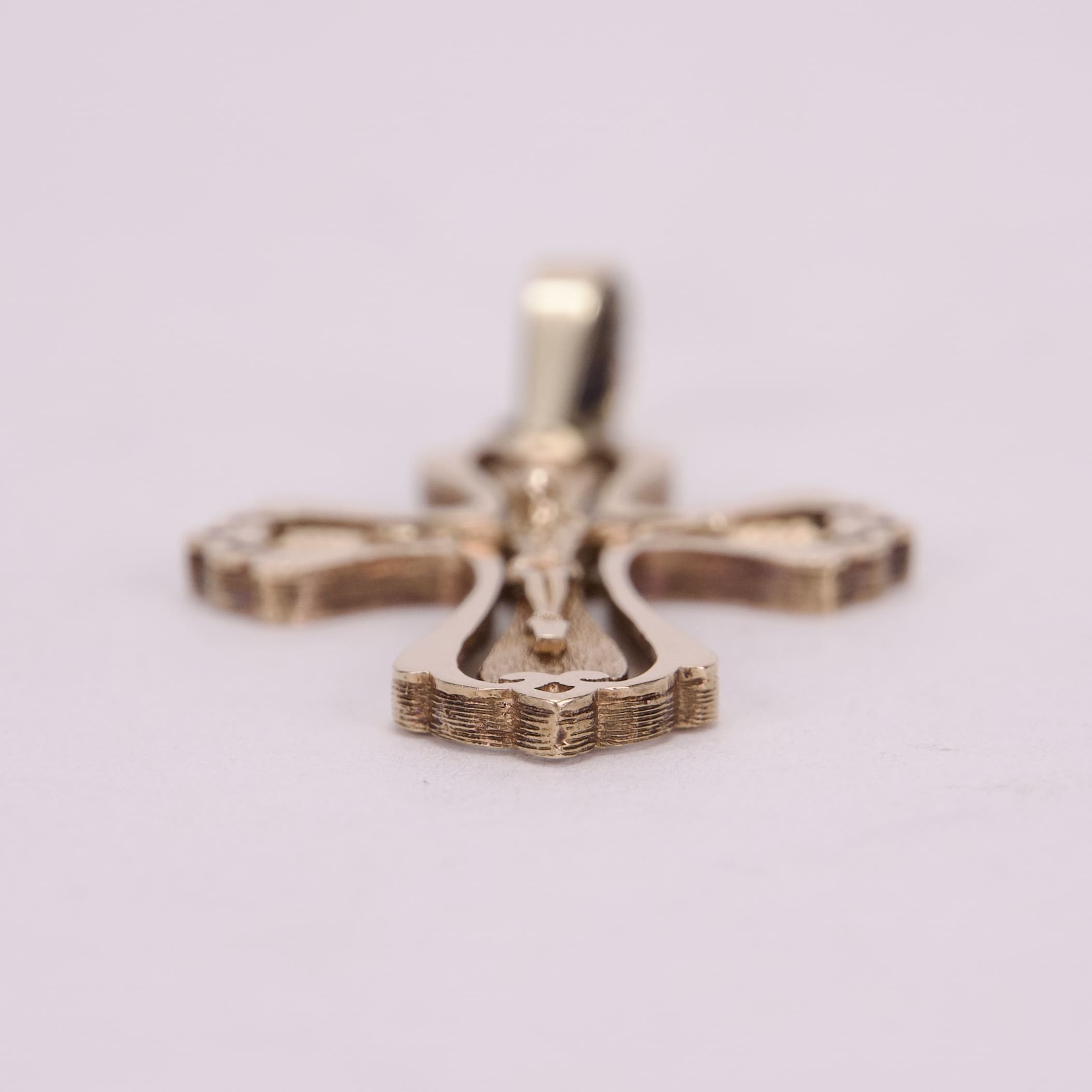Gold cross pendant on soft background.