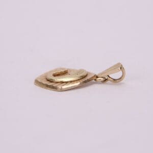 Golden pendant with loop on light background.