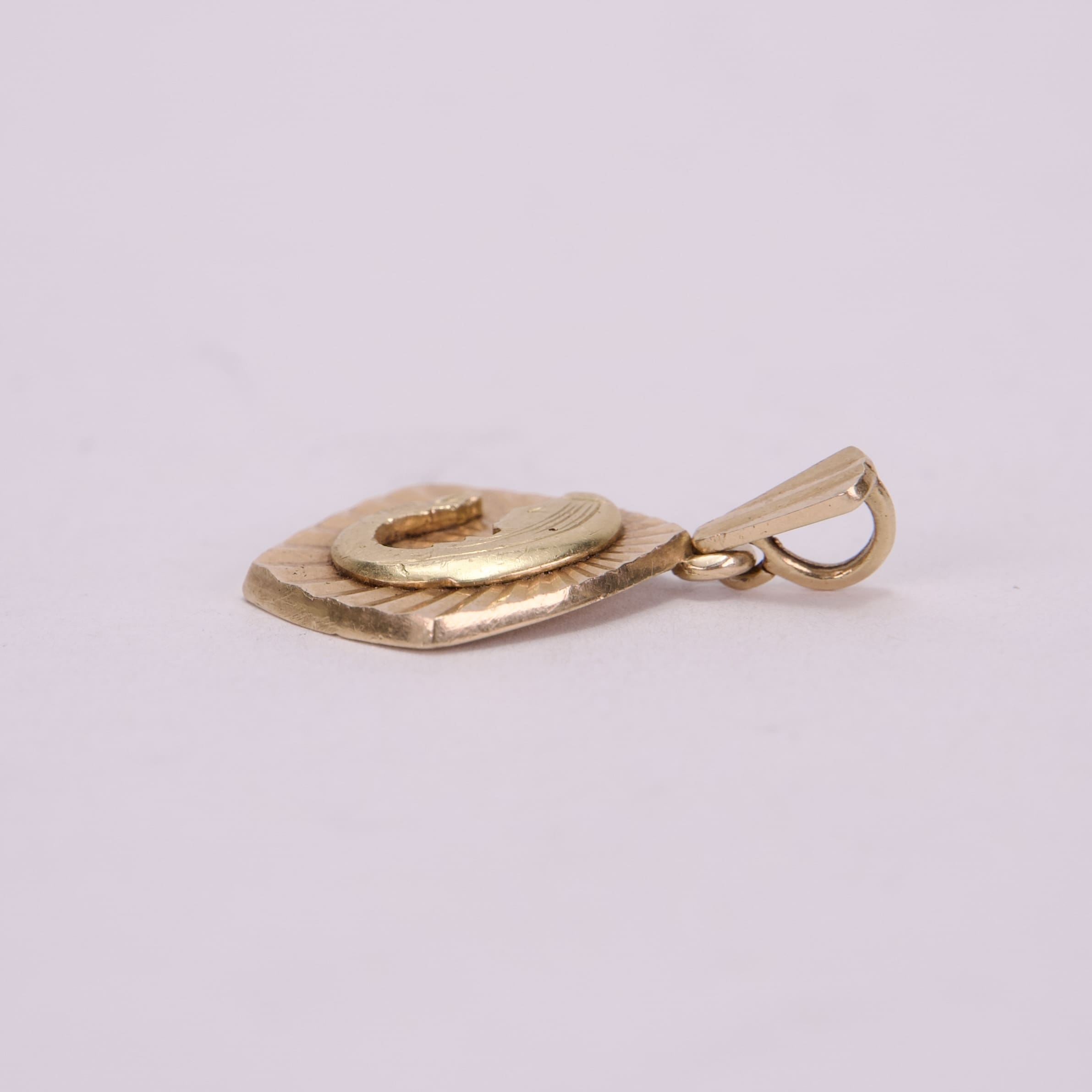 Golden pendant with loop on light background.