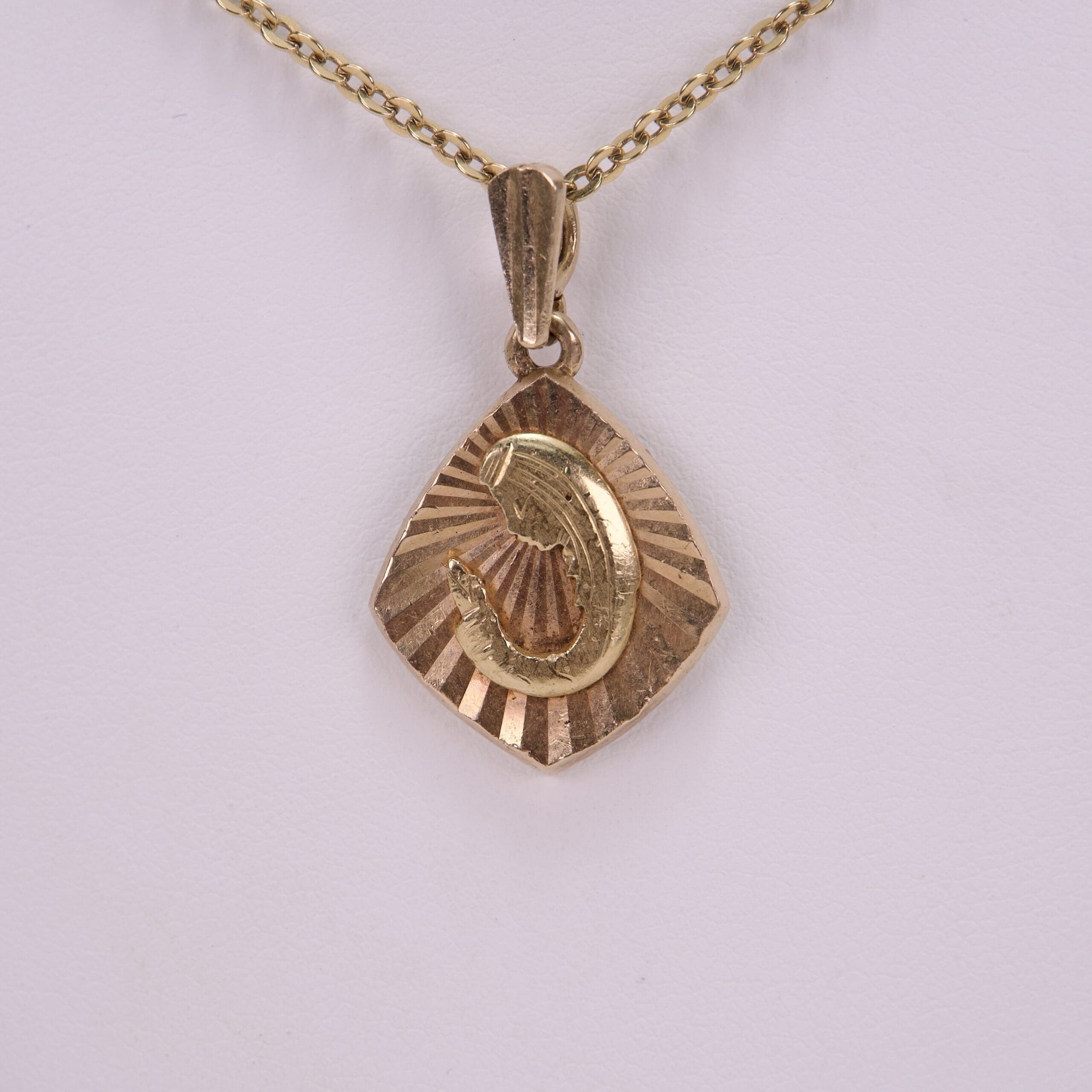 Gold pendant with engraved figure on chain.