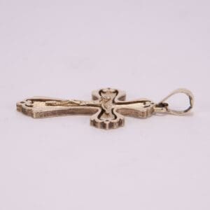 Gold cross pendant on light background.