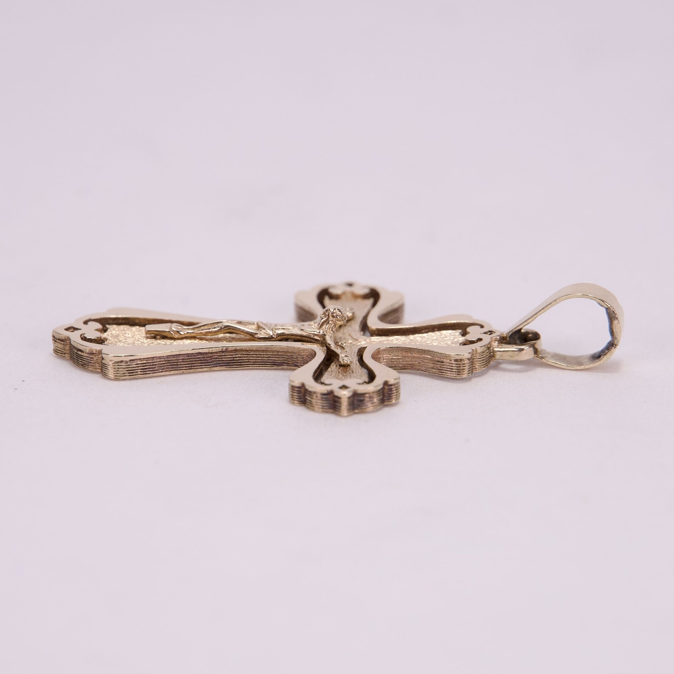 Gold cross pendant on light background.