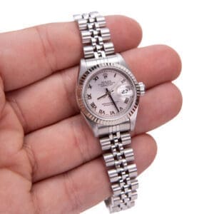 Hand holding a silver wristwatch with date.