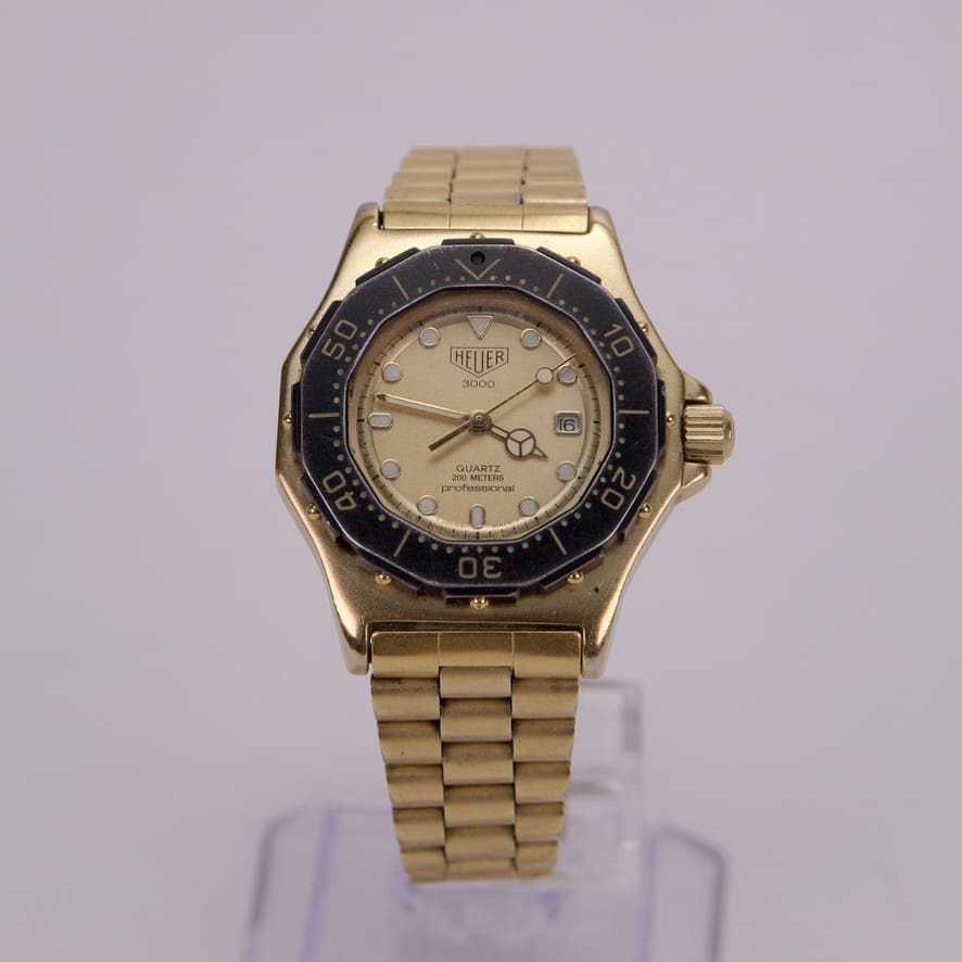 Gold wristwatch with black bezel on display.