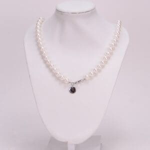 Pearl necklace displayed on white mannequin bust.