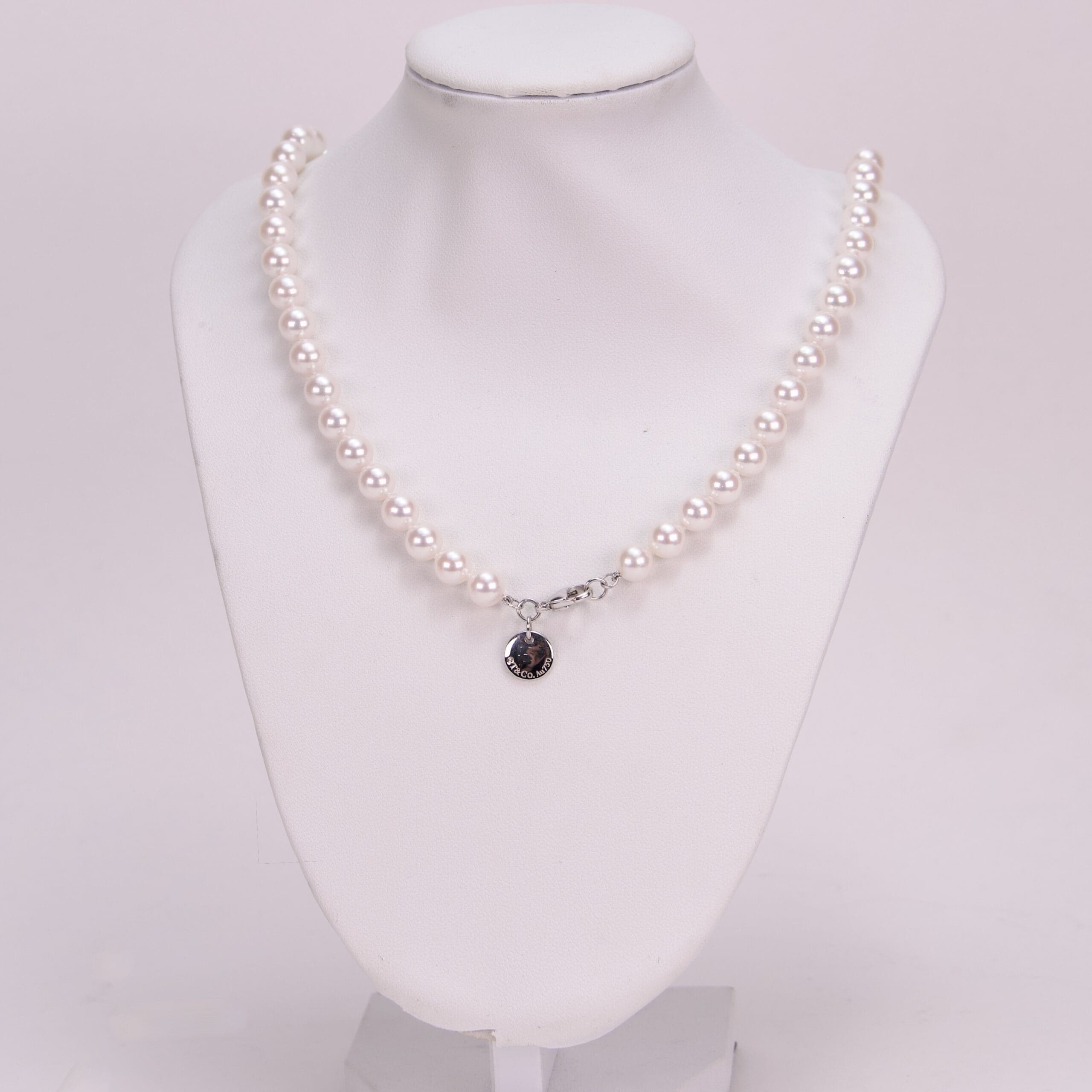 Pearl necklace displayed on white mannequin bust.